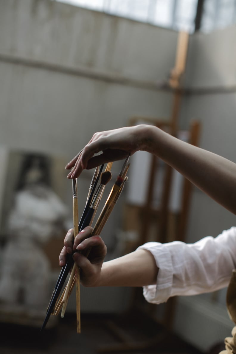 Person in White Long-Sleeve Shirt Holding Paint Brushes